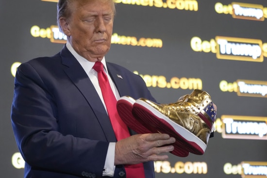 Republican presidential candidate former President Donald Trump holds gold Trump sneakers at Sneaker Con Philadelphia, an event popular among sneaker collectors, in Philadelphia, Saturday, Feb. 17, 2024. (AP Photo/Manuel Balce Ceneta)