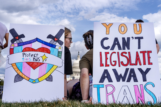 With the U.S Capitol seen between them, people sit by signs saying "protect trans kids," and "you can't legislate away trans" as they attend a rally for the Trans Day of Visibility, on the National Mall, Monday, March 31, 2025, in Washington. (AP Photo/Jacquelyn Martin) With the U.S Capitol seen between them, people sit by signs saying "protect trans kids," and "you can't legislate away trans" as they attend a rally for the Trans Day of Visibility, on the National Mall, Monday, March 31, 2025, in Washington. (AP Photo/Jacquelyn Martin)
