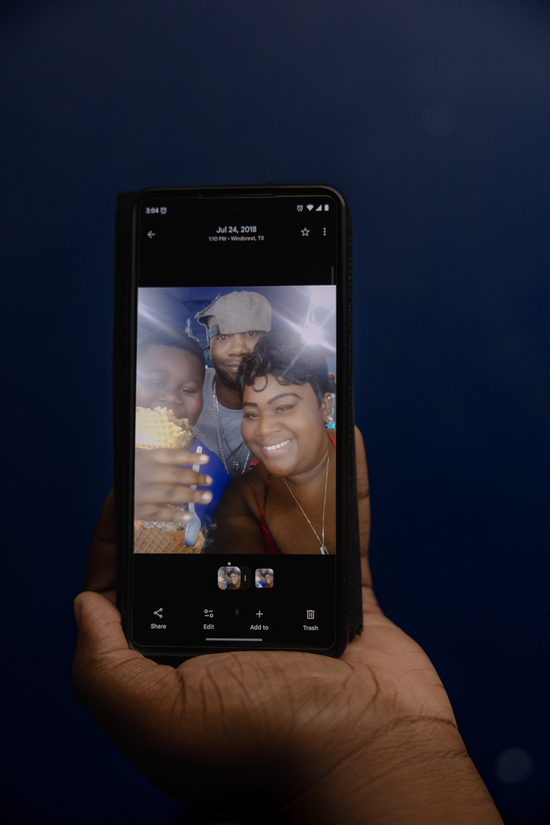 Javohn , “JJ,” Tierra’s son, holds up his favorite picture, Saturday, Oct. 4, 2025, in San Antonio. The photo is of a younger JJ, his biological dad and his mom. Both of his parents have passed. He says that when he misses his mom, he looks at pictures like these. A reserved, respectful kid, all of Tierra’s family watches over JJ, helping him through his grief. ..(Lexi Parra for ProPublica)